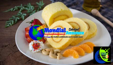 Sponge cake roll with cream, strawberries and orange fruits on a white plate on wooded table background. Rouleau à l'Orange