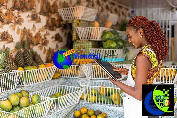Successful African female business owner of fresh produce store and grocery shop uses a smart tablet to video call customers and take orders remotely. MondialAnnonce, un tremplin pour les petits vendeurs et les entrepreneurs sénégalais